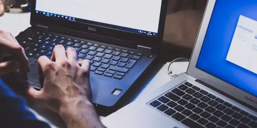 Person Typing On Two Laptops Resized Esm W900